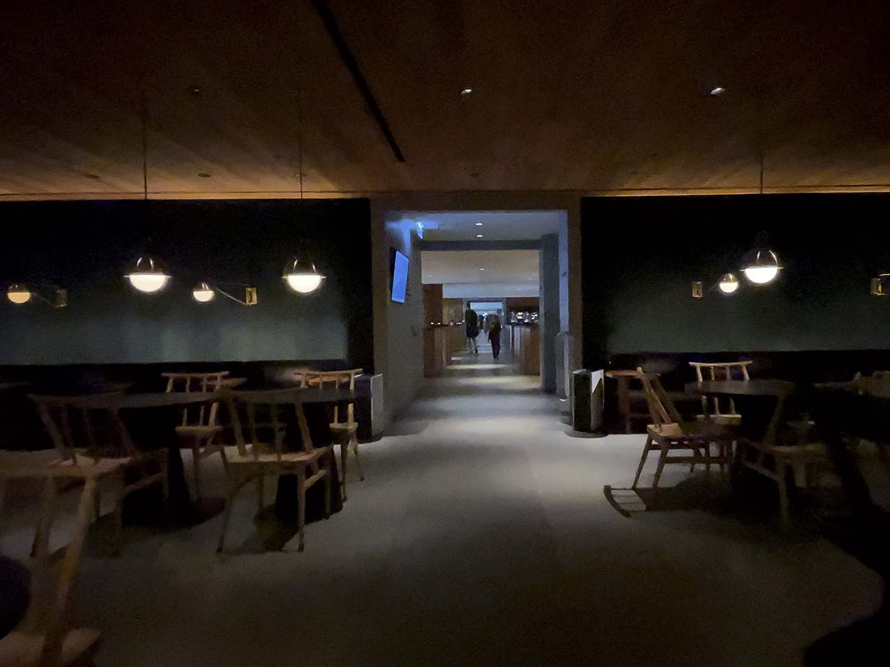 Dark rooms with cafeteria style tables and chairs inside the Cathay Pacific The Pier Lounge Hong Kong